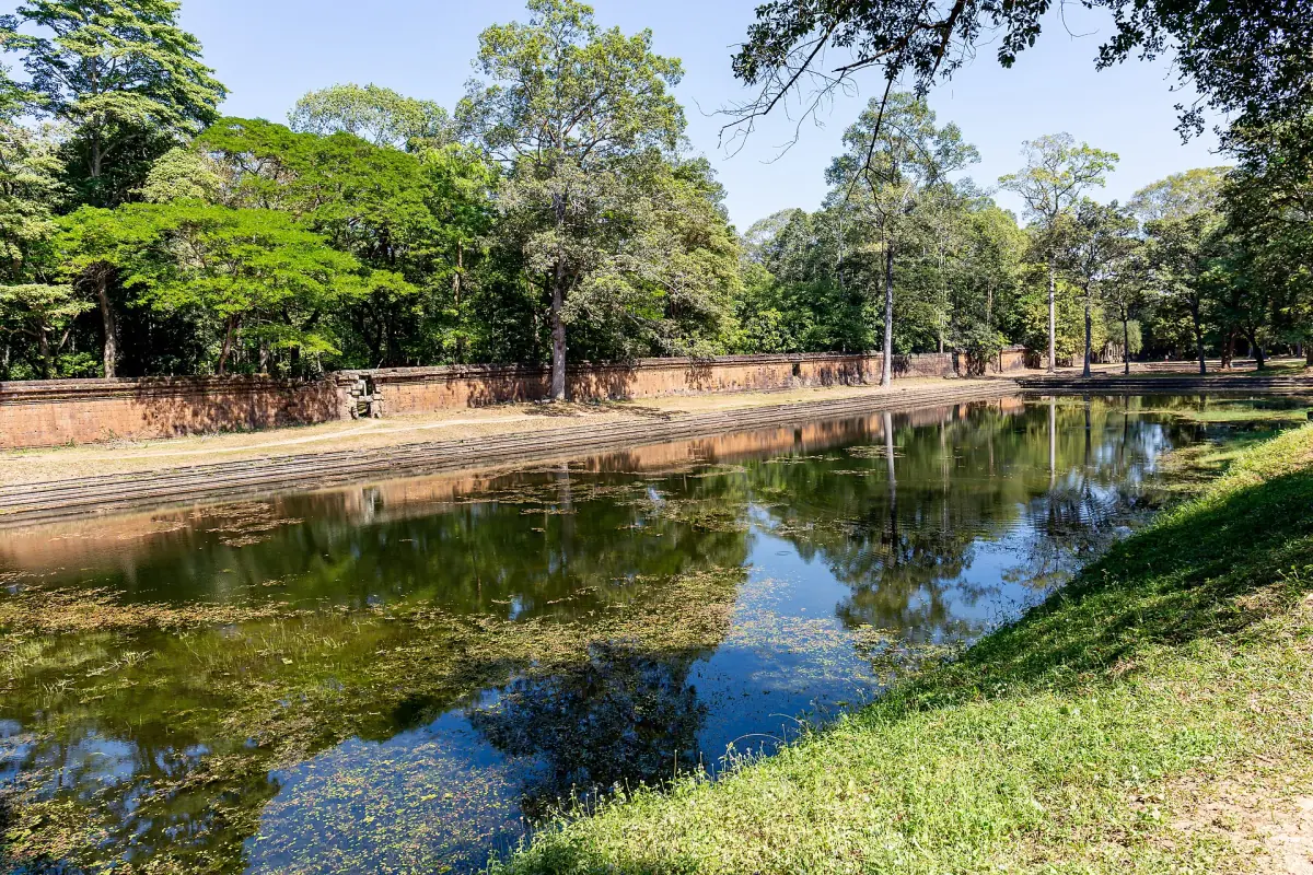 Still pond with reflections beside a laterite wall
